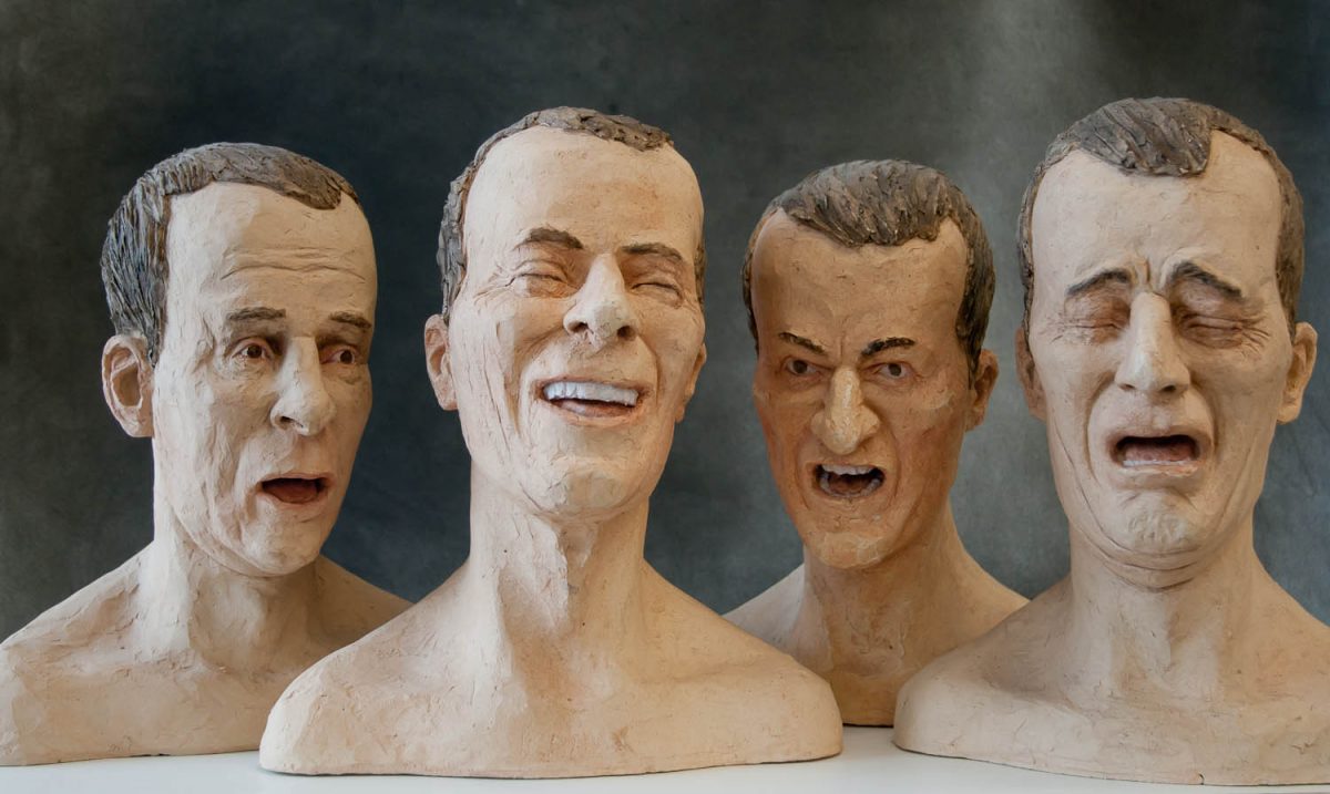 four male heads expressing emotion, the heads may be made of rubber. they look creepy.